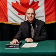 Dave Dyment pose pour une photo devant un drapeau du Canada.