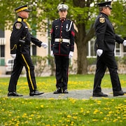 Trois policiers en uniforme qui défilent. 
