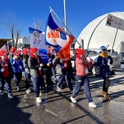 La délégation de la Côte-Nord marche dans une rue avec le drapeau de la délégation et des bannières.