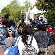Une file de demandeurs d'asile attendent de franchir un point de contrôle installé au bout du chemin Roxham, à Saint-Bernard-de-Lacolle.