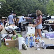 Un groupe de jeunes sort des boîtes et des meubles d'un véhicule et les place sur le trottoir.