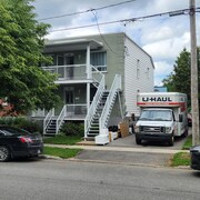 Un camion de déménagement est stationné à côté d'un duplex. Des meubles sont placés juste à côté.