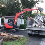 Une pelle mécanique démolit une maison mobile.