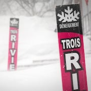 Des pancartes de Déneigement Trois-Rivières dans une rue enneigée.