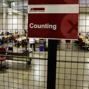 Des agents comptent des bulletins de vote qui ont été reçus par la poste lors de l'élection fédérale de 2021.