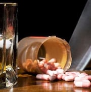 Un verre d'alcool et une bouteille de comprimés sur un bar