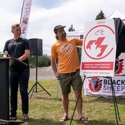 Eric Bailey et deux autres personnes dévoilent un logo.