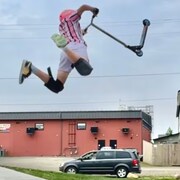Dex Foster faisant une figure acrobatique avec sa trottinette.