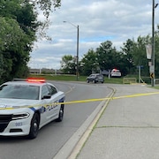 Une voiture de police derrière un ruban policier.
