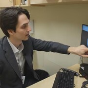 Un homme pointe un moniteur d'ordinateur qui affiche une radiographie de poumons.