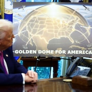Donald Trump semble regarder une pancarte avec le message «Dôme d'or pour l'Amérique» sous une carte de l'Amérique du Nord où des missiles sont détruits.