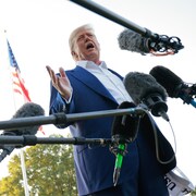 Donald Trump parle devant plusieurs micros.