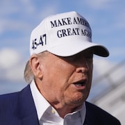 Donald Trump arbore une casquette Make America Great Again sur le tarmac de l'aéroport.