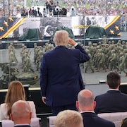 Donald Trump, de dos, fait un salut militaire à des troupes qui défilent devant lui à Washington le 14 juin 2025.