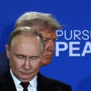 Donald Trump est partiellement caché par Vladimir Poutine qui est debout en face de lui.