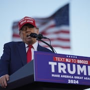 Donald Trump porte une casquette MAGA et parle dans un micro.