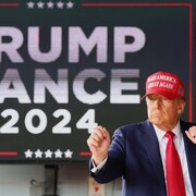 Donald Trump se tient debout, les poings à la hauteur du visage. 