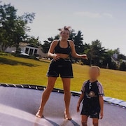 Donna et son fils sautent sur une trampoline. 