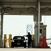 Un douanier s'approche d'une voiture à la frontière canado-américaine.