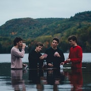 Quatre jeunes hommes dans un lac avec de l'eau jusqu'à la moitié du corps
