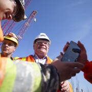 Portant un casque, Doug Ford sourit sur un chantier de construction.