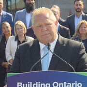 Doug Ford debout à un podium devant les ministres ontariens.