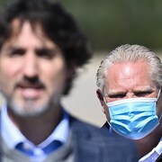 Le premier ministre ontarien Doug Ford se tient derrière Justin Trudeau. 