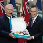 Le premier ministre Doug Ford et le maire d'Ottawa, Mark Sutcliffe, posent avec une boîte de beignes.