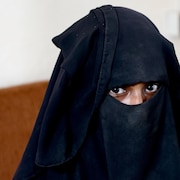 Une femme portant le niqab fixe la caméra.