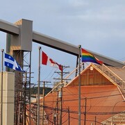 Le drapeau arc-en-ciel flottent devant l'usine aux côtés des drapeaux du Québec et du Canada. 