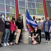 Plusieurs personnes autour du drapeau qui s'apprête à être hissé.