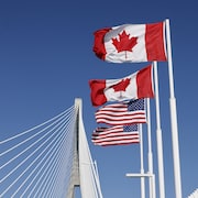Les drapeaux du Canada et des États-Unis flottent de part et d'autre de la frontière internationale sur le pont international Gordie-Howe, qui relie Windsor, en Ontario, à Détroit, dans le Michigan.