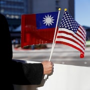 Un homme tient des drapeaux de Taïwan et des États-Unis.