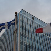 Photo en contreplongée des drapeaux du Québec et de la France. On aperçoit, à l’arrière-plan, l’édifice abritant le Consulat général de France à Québec.