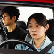 Un homme japonais est assis sur la banquette arrière d'une voiture conduite par une jeune japonaise.