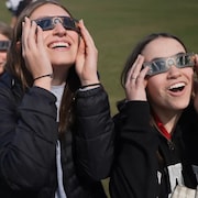 Deux adolescentes regardant le soleil avec des lunettes.