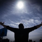 
Un homme tend les bras vers le ciel pendant l'éclipse totale du Soleil.
