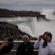 Des visiteurs devant les chutes Niagara avec leurs lunettes protectrices pour l'éclipse.