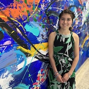 Une adolescente pose devant une murale.