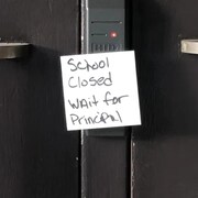 Les portes d'une école sont barrées avec un écriteau "école fermée, attendre le directeur". 
