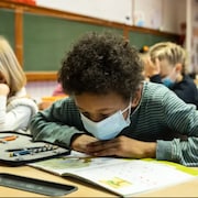 Des enfants en classe lisant des manuels.