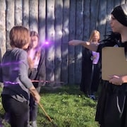 Une femme utilise sa baguette magique entourée de jeune filles. Image prise de YouTube le 8 février 2022.