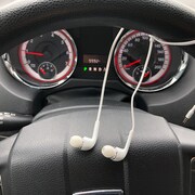 Des écouteurs pendent au volant d'une voiture.
