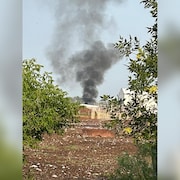 Le lieu de l'écrasement des avions. Une épaisse colonne de fumée noire s'élève dans un ciel clair.