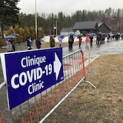 Des gens qui attendent en ligne sous la pluie.