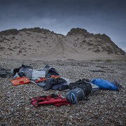 Des effets personnels de migrants et un canot pneumatique dégonflé sur une plage.