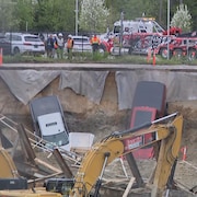 Des camionnettes gisent parmi les décombres dans un grand trou.
