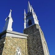 Vue en contre-plongée du clocher de l'église de L'Isle-Verte lors d'une journée ensoleillée.