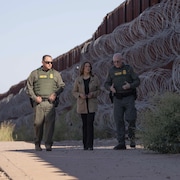 Mme Harris marche le long de la frontière avec deux hommes en uniforme.