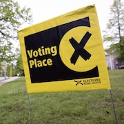 Petit drapeau jaune et noir planté dans la pelouse annonçant la proximité d'un bureau de vote en Nouvelle-Écosse.